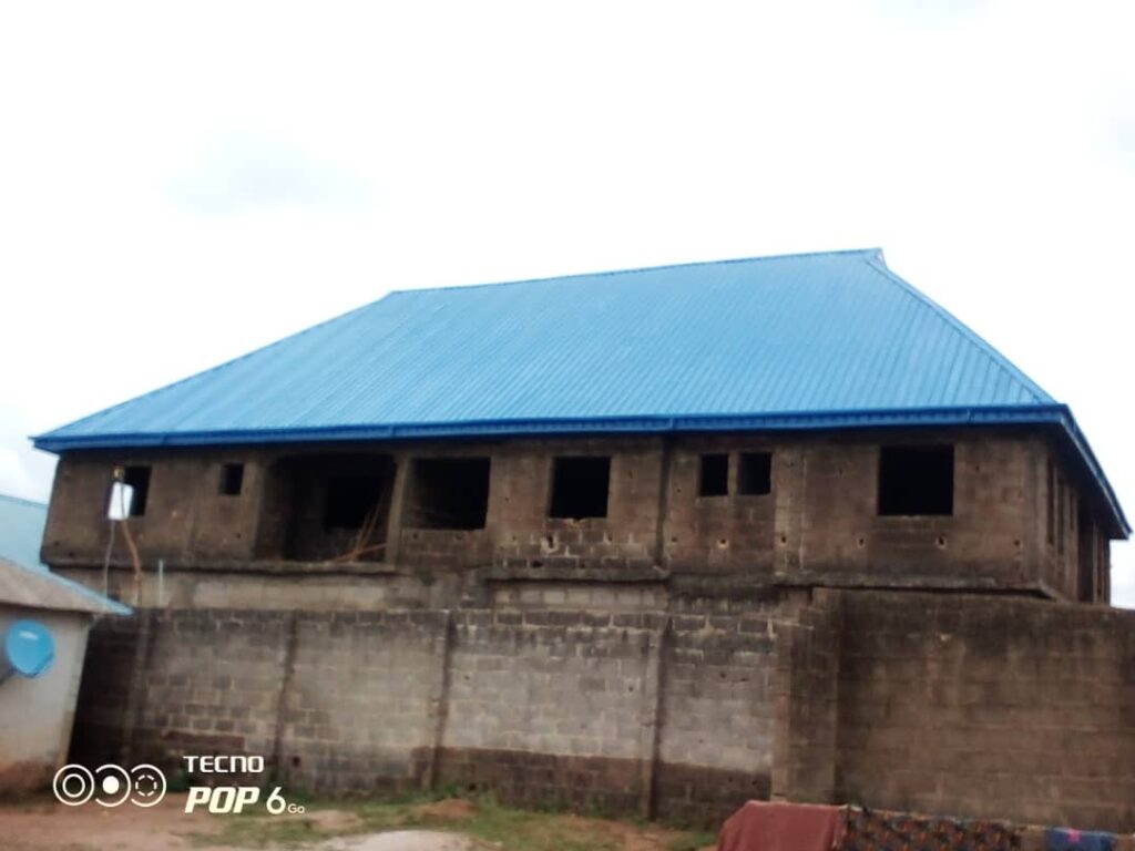 Bright blue aluminium roof on a two-story block building by Blessed Joe Aluminium.